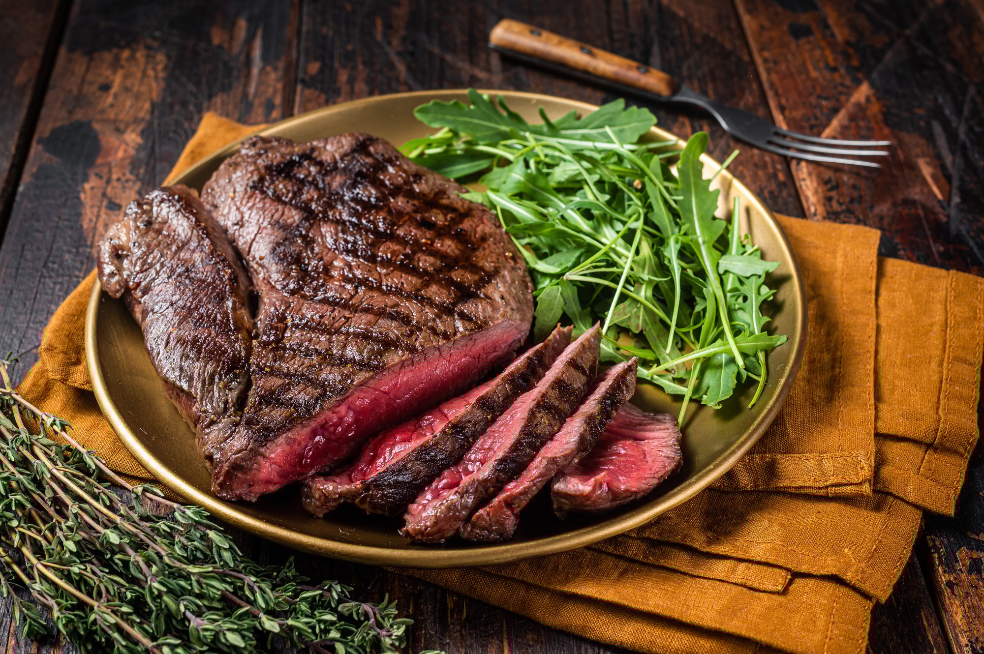 BBQ dinner with top sirloin beef steak and salad on a plate. Wooden background. Top view